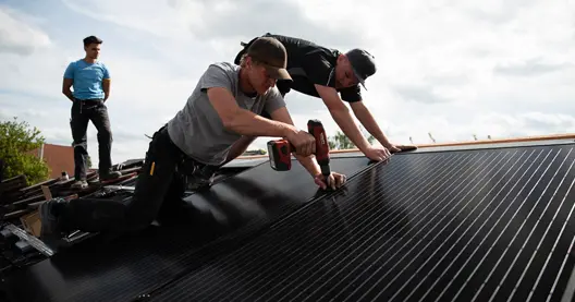 Handwerker montieren Solaranlage am Dachfirst