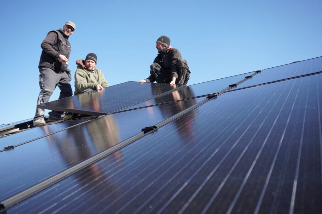 Partnerprogramm Photovoltaik für Verarbeiter – Team montiert Solarmodule auf geneigtem Dach.