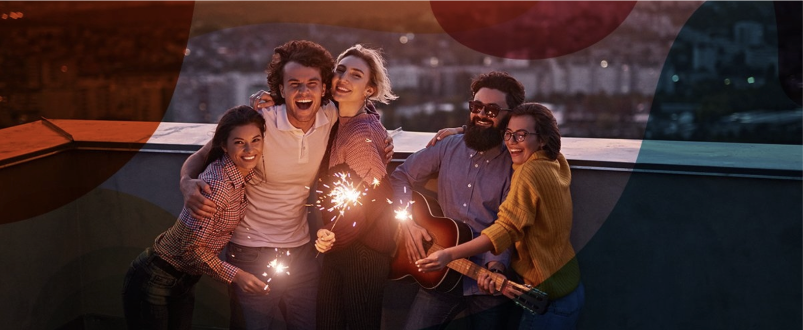 Freunde feiern mit Wunderkerzen auf Dach vor funkelnden Stadtlichtern