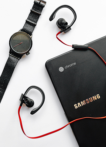 Samsung Chromebook, schwarze Armbanduhr und rote In-Ears