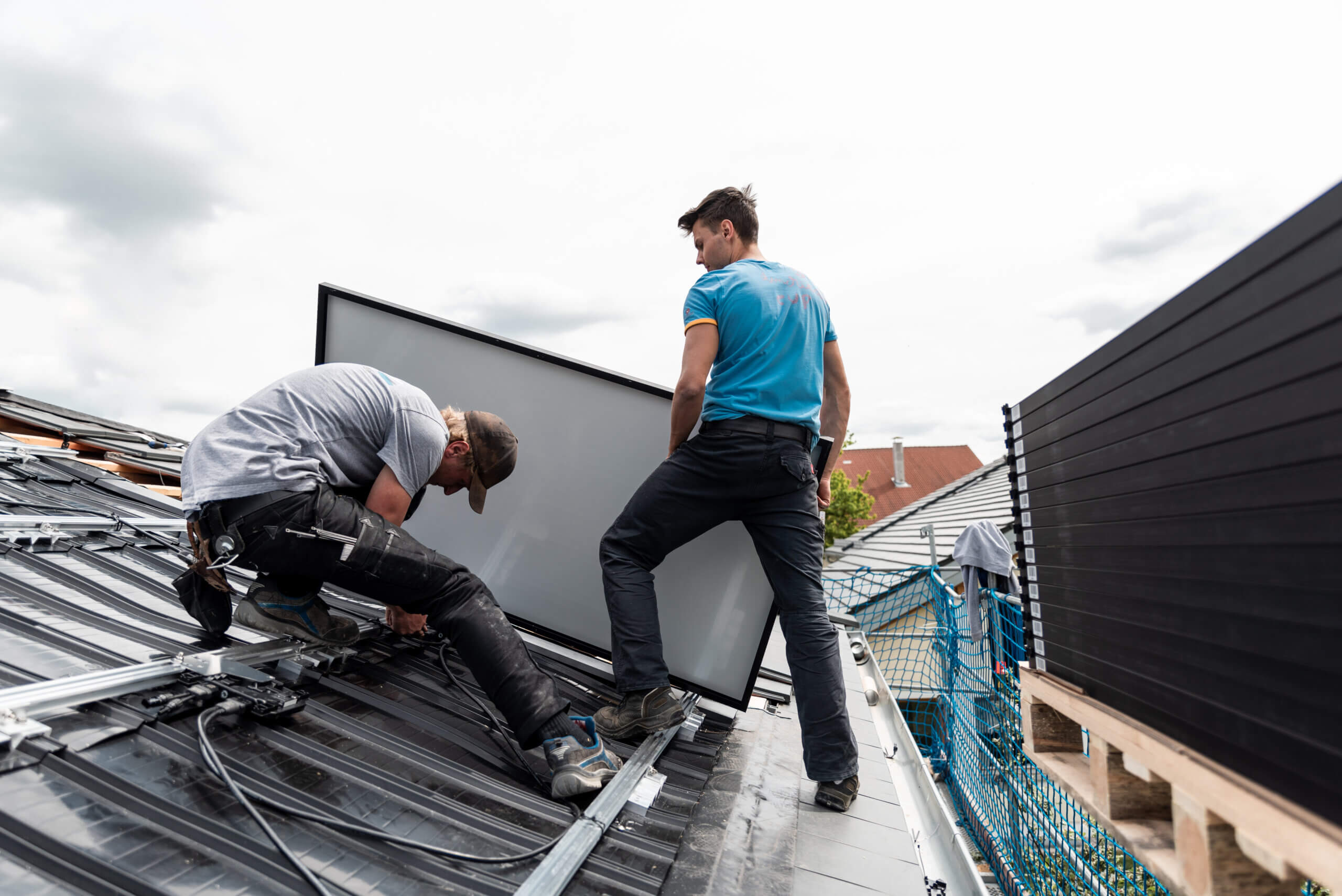 Partnerprogramm Photovoltaik für Verarbeiter: Monteure montieren Solarmodul auf Schrägdach