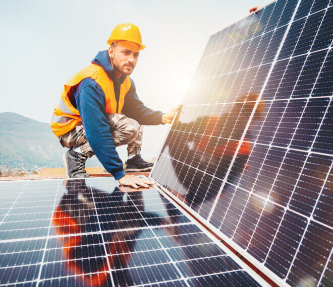 Solarmonteur kniet an Photovoltaikmodulen zur Wartung in Solarpark