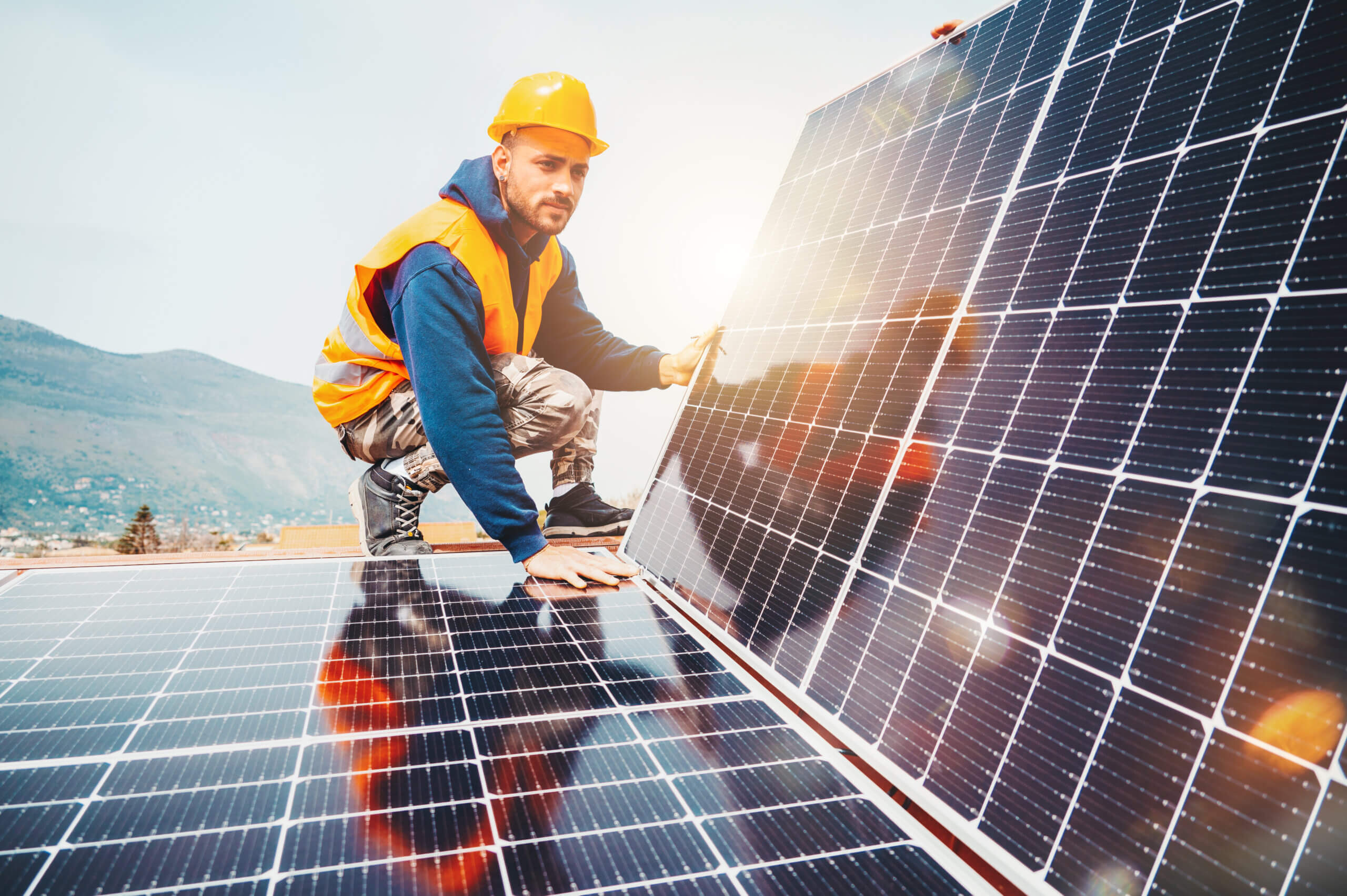 Solarmonteur kniet an Photovoltaikmodulen zur Wartung in Solarpark