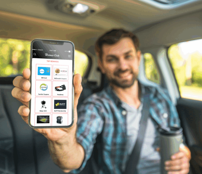 Mann zeigt Smartphone mit Vorteilsprogramm für Lkw‑Fahrer im Auto