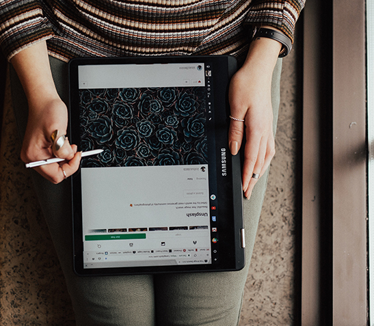Hände mit Stylus bei digitaler Bildbearbeitung auf Tablet im Schoß