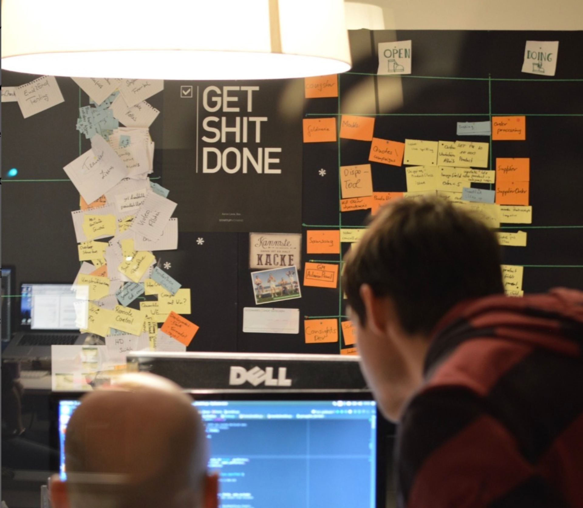Teamarbeit am Monitor mit Kanban-Board und bunten Post-its
