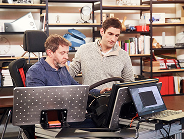 Zwei Techniker beim Prototypentest mit Laptop und Steuergerät in Werkstatt