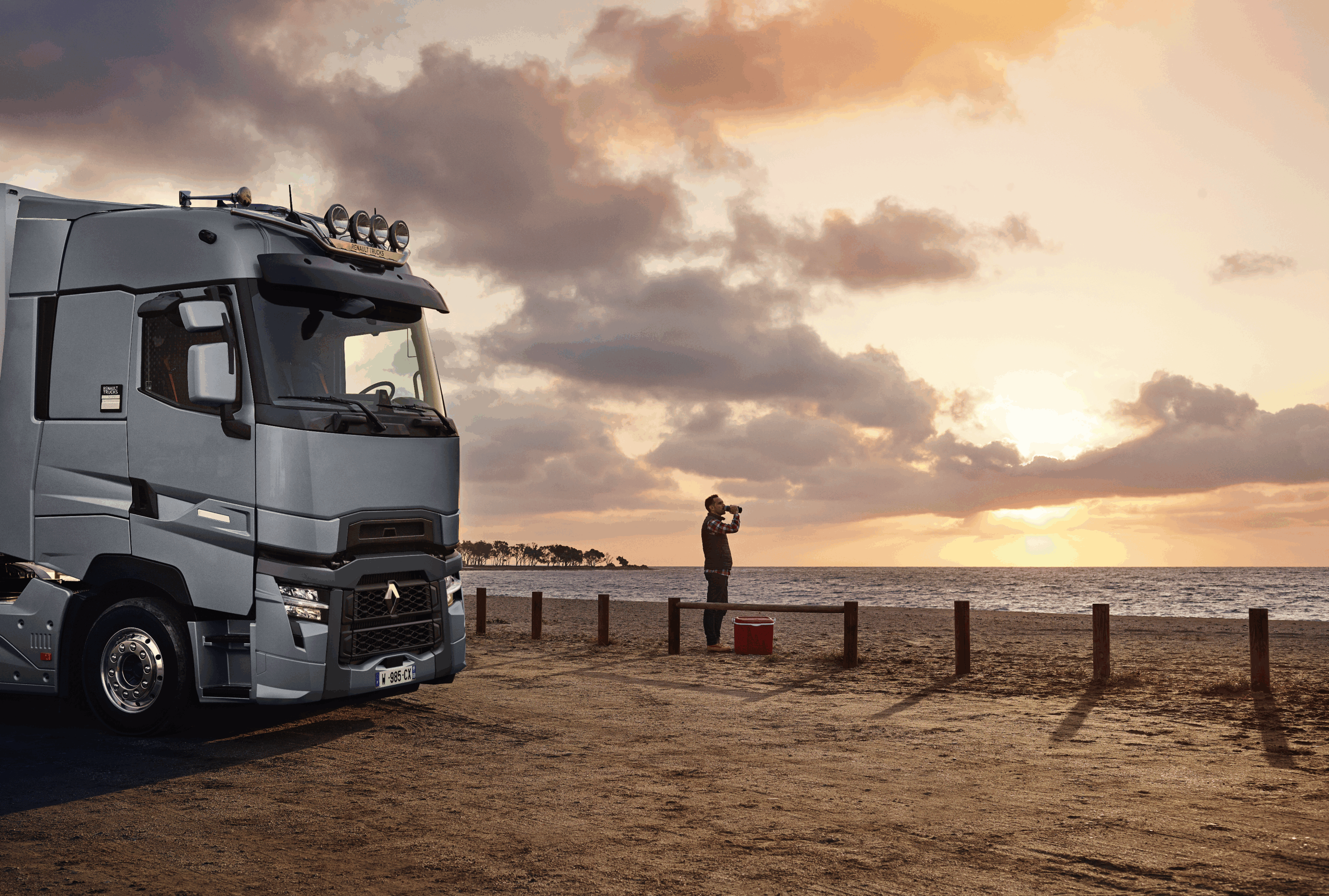 Parkender Lkw am Strand bei Sonnenuntergang, Person beobachtet das Meer