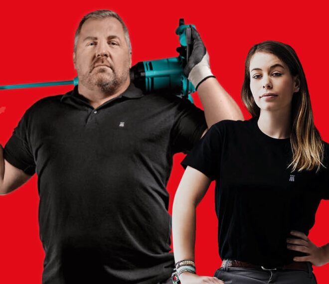 Handwerkerduo mit Profi-Bohrhammer vor rotem Hintergrund, stark und souverän