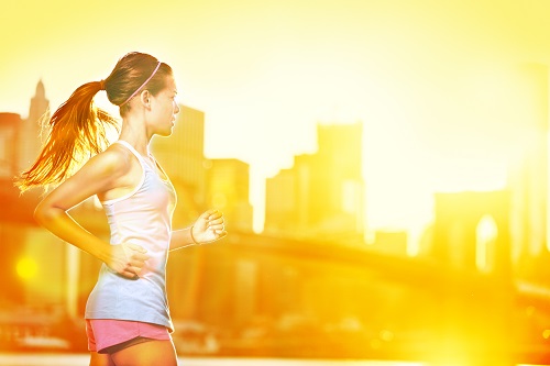 Läuferin in der Stadt bei Sonnenaufgang vor goldener Skyline