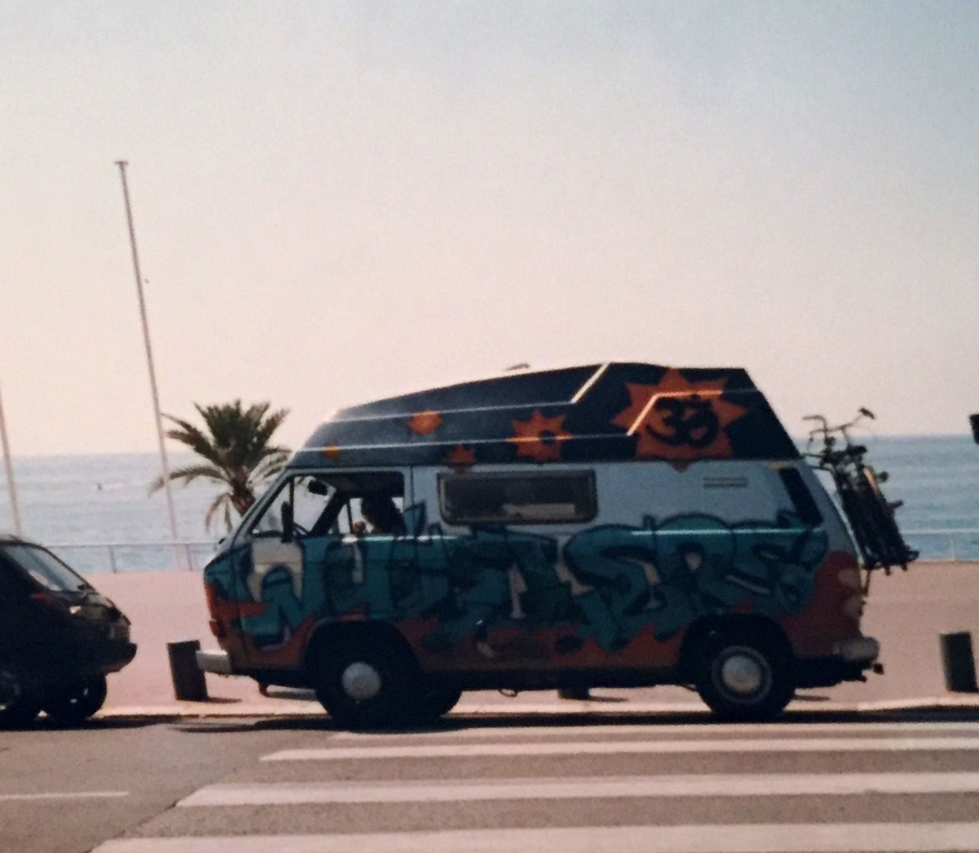 Bunter Vintage-Camper mit Fahrrad, Graffiti-Design an der Küste