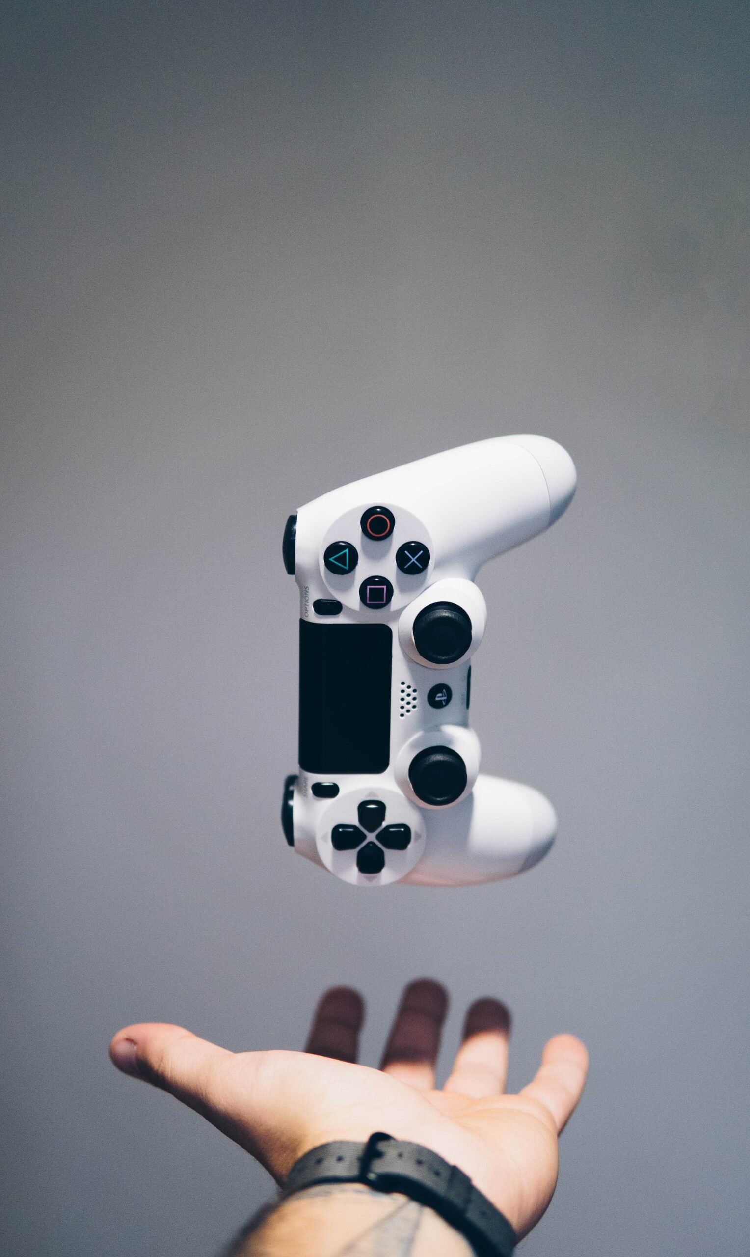 Schwebender weißer Gaming-Controller über offener Hand vor neutralem Hintergrund