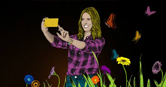 Frau macht Selfie mit gelbem Smartphone vor Blumenmeer und Schmetterlingen