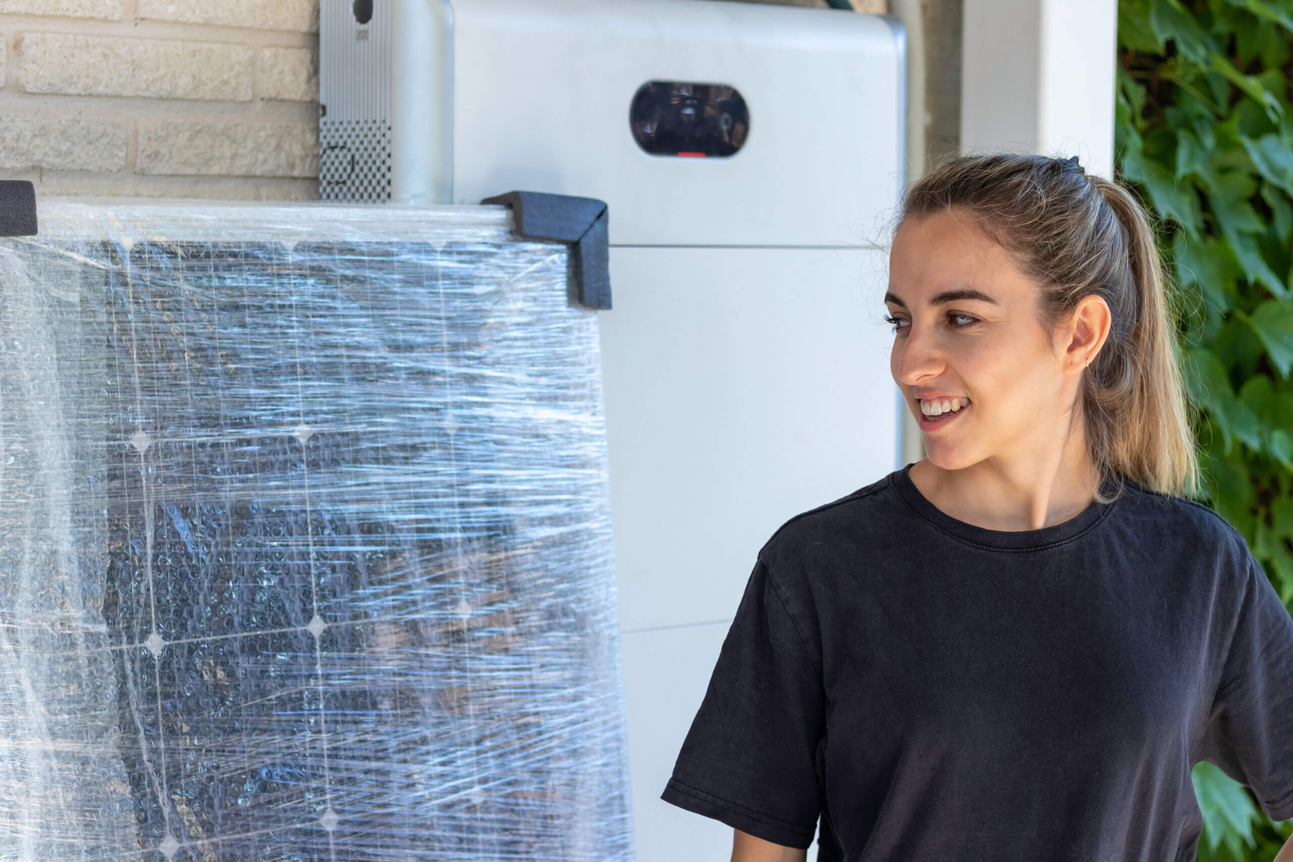 Frau neben verpacktem Solarmodul zur Hausinstallation, Solarpanel für erneuerbare Energie