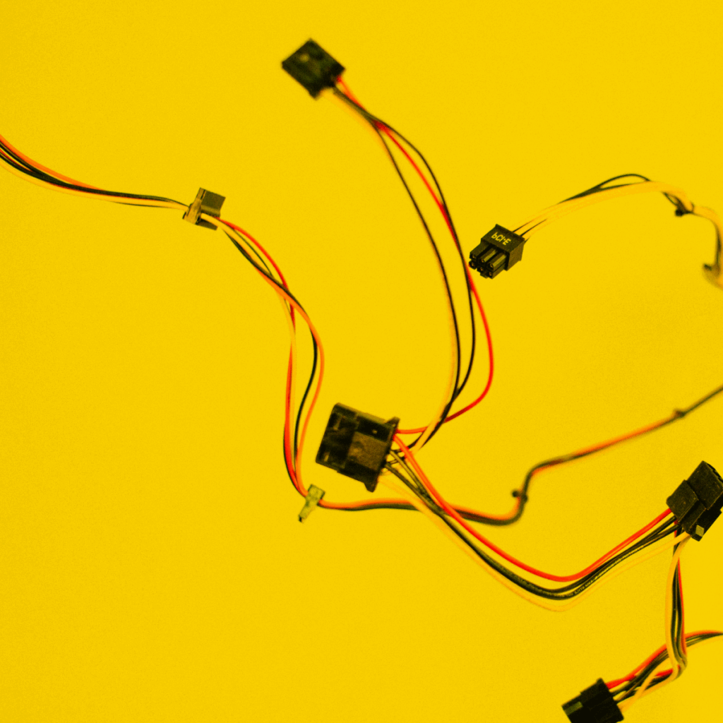 Bunte Elektronik-Kabel mit Steckverbindern vor gelbem Hintergrund