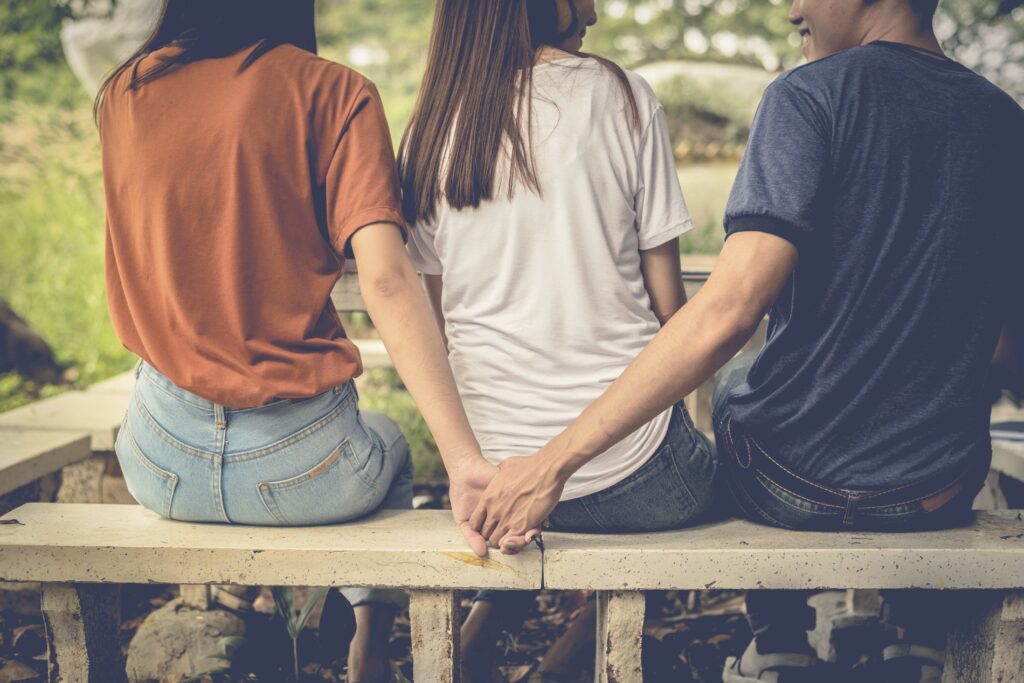 Zwei Personen sitzen zusammen auf einer Couch und diskutieren, während ein dritter Freund entspannt daneben sitzt